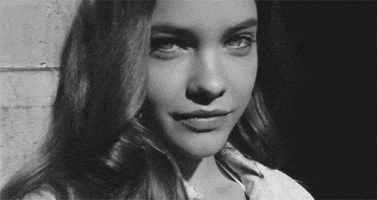 Celebrity gif. Model Barbara Palvin looks at us and winks.
