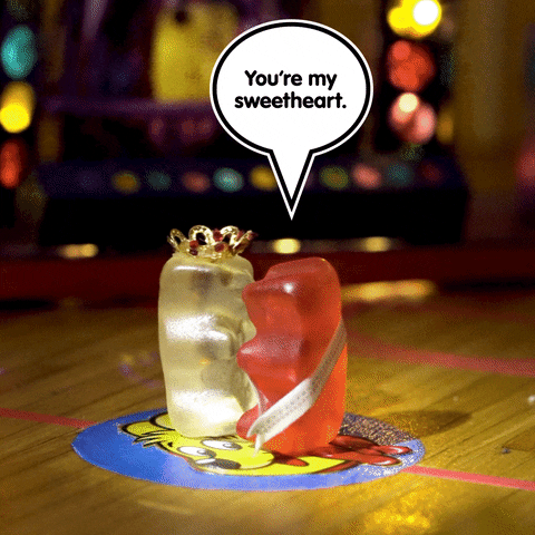 Stop motion gif. Two Haribo Gold Bears dressed like the homecoming queen and king slow dancing as lights flash behind them. Text, "You're my sweetheart."