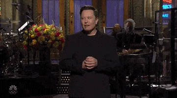 SNL gif. Elon Musk as host turns his palms out in a shrug as he rolls his eyes with a bewildered expression.