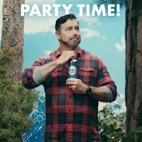 Sponsored gif. Gerald Downey looks around with a content expression standing among pine trees and snow capped mountains in the distant background. He cracks a can of beer as a deer, owl, and squirrel pop into frame as Downey looks at us with confused acceptance. Text, "Party Time."