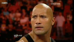Sports gif. Dwayne "The Rock" Johnson is in the WWE ring. His bald head glistening, he breaks into a wide and mischievous smile. He's about to throw down in the best way.