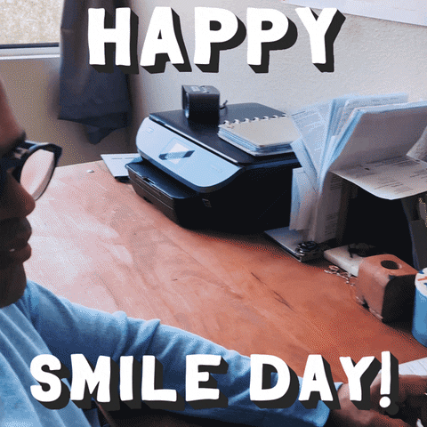 Video gif. A man turns to us and smiles revealing comical fake rubber teeth. Text, "Happy smile day!"