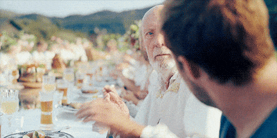 Movie gif. Björn Andrésen as Dan in Midsommar looks annoyed and claps his hands in the face of Jack Reynor as Christian. The two are seated at a long wedding dining table. As the man claps, the background warps in a trippy way.