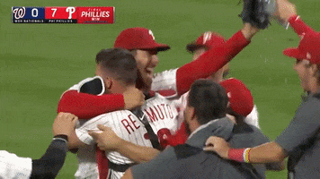 Sports gif. Two women in the stands at a Phillies game are crying and cheering, holding up their phones to capture the moment. The frame changes to Phillies baseball players jumping for joy and looking victorious. 