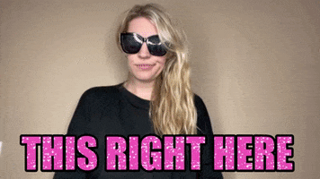 Video gif. A blonde girl with blacked out sunglasses that take up half of her smug smirking face points up above her. The sparkly pink text reads, “This right there.”