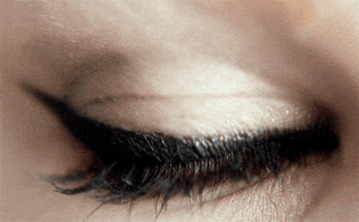 Video gif. A close up on a woman’s light blue eye blinking open and then closed. 