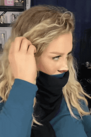 Video gif. A woman has pulled her turtleneck and scarf up to cover her mouth. She has painted red lips on the bottom of her nose and a smaller nose above that. She whips her head to look at us and then whips it around against to give us a questioning look.