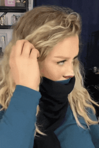 Video gif. A woman has pulled her turtleneck and scarf up to cover her mouth. She has painted red lips on the bottom of her nose and a smaller nose above that. She whips her head to look at us and then whips it around against to give us a questioning look.