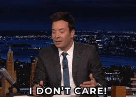 Late Night gif. Jimmy Fallon sits at his desk, squinting his eyes and shaking his head as he says, “I don't care.”