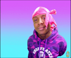 Video gif. Man in a hot pink durag and purple camo hoodie looks up at us with a smile and waves.