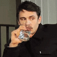 Celebrity gif. James Franco sips on a glass of water, side eyeing something judgmentally, and slowly swallows the water.