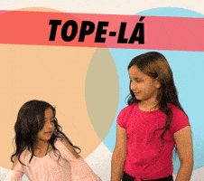 Video gif. Two little girls try to high five each other and miss, then both turn around laughing. Text, in Portuguese, reads "Tope-lá."