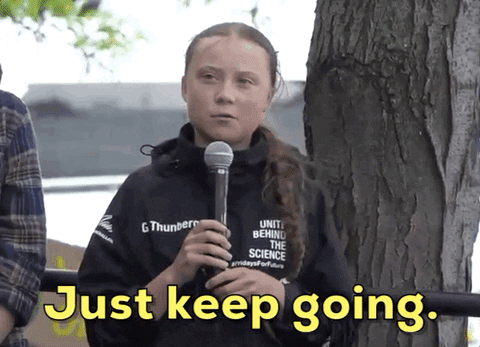 Greta Thunberg holding a microphone and speaking to a crowd, caption reads 'Just keep going'