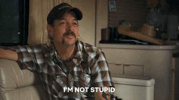 TV gif. Joe Exotic from The Tiger King sits on a couch, nods and smiles, and says, "I'm not stupid."
