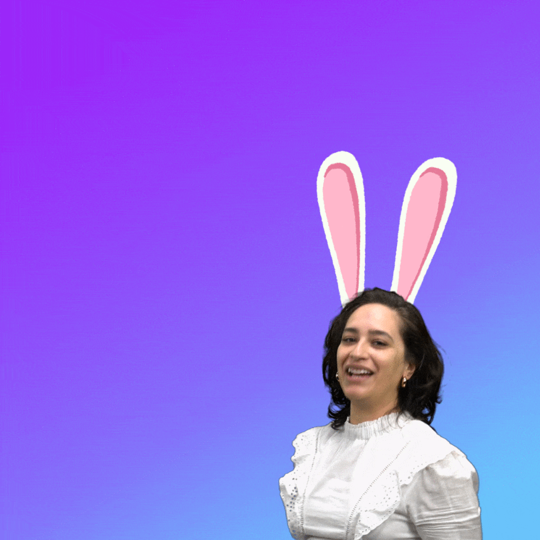 Video gif. Woman with cartoon bunny ears does a shoulder shimmy as she purses her lips, smiles, and winks in front of a background that fades from lilac to sky blue. Text, "Happy Easter."