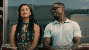 TV gif. Sterling K. Brown as Randall and Susan Kelechi Watson as Beth on This Is Us sit next to each other with proud expressions on their faces. Randall reaches over, holds his hand out and she grabs onto it tightly.  