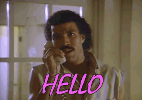 Celebrity gif. Lionel Richie, in a scene from his "Hello" music video, holds a phone to his ear, looks into the camera and sings, "Hello."