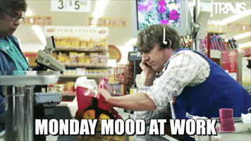 Video gif. A cashier at a grocery store leans onto the check out area with a bored, apathetic expression on his face. He chucks a bouquet of yellow roses off the conveyor belt and behind him. tHe older lady in front of him gasps in shock. Text, “Monday mood at work.”