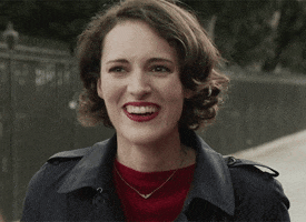 TV gif. On a sidewalk, Phoebe Waller-Bridge as Fleabag smiles and laughs politely, then she looks at us and frowns.