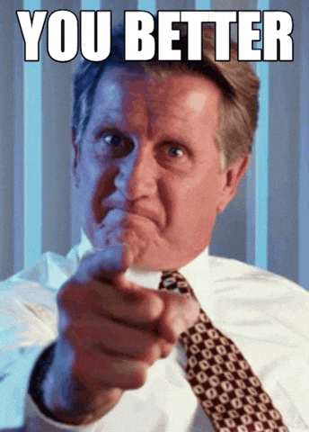 Video gif. A man with a fierce face points a firm and shaking finger directly at us. 