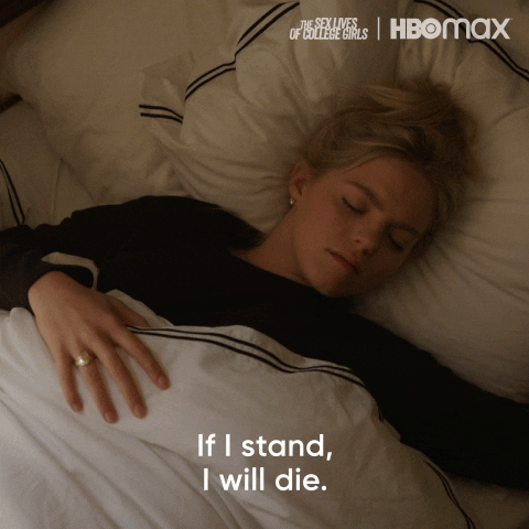 TV gif. Reneé Rapp as Leighton in The Sex Lives of College Girls. She's laying in bed after a night out and she looks incredibly hungover as she says, "If I stand, I will die."
