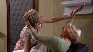 TV gif. Character from Thuis with blonde hair who appears to be laying on a medical exam table laughs hysterically as she yanks another woman by the hair, possibly trying to keep her away from the object she is holding in one hand. A man enters the room and in a panic tries to stop the commotion.