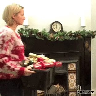 Video gif. Woman in a Christmas sweater holding a tub of decorations approaches a bare Christmas tree, seemingly annoyed at the prospect of decorating it. She throws the contents of the tub directly at the tree, and they land on it, perfectly arranged. The woman nods in satisfaction as the tree lights up.