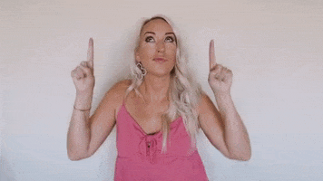 Video gif. Chelsie Kenyon, a marketing coach, pouts her lips and looks upwards while also pointing upwards, giving a little bouncy dance to emphasize her pointing. 