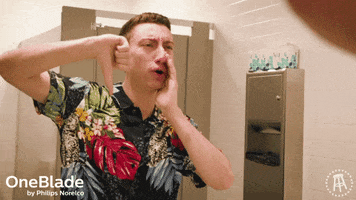 Ad gif. A young man stands in a public restroom pumping a thumbs down and cupping a hand beside his mouth as he shouts, "Boo!" Logo in the corner reads Philips Norelco One Blade.