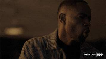 TV gif. Jay Ellis as Lawrence on Insecure leans back and away from something as he blows into his fist like he can barely stand to watch what he's looking at. 