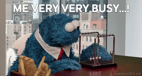 a cookie monster is sitting at a desk with a newton 's cradle .