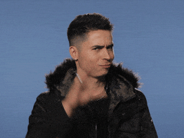 Celebrity gif. Reykon wears a fur-lined parka and a smirk as he opens and closes his fingers like a blabbing mouth, then waves his hand away.