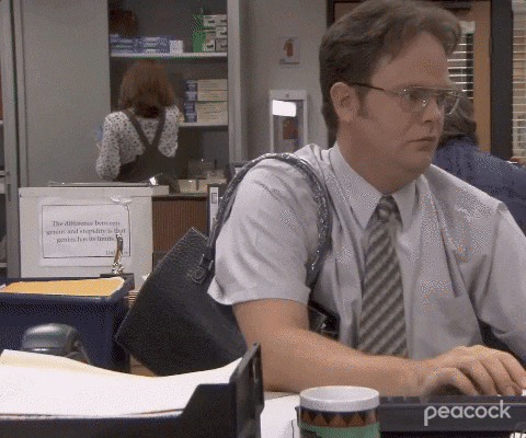 Dwight works at his desk wearing the handbag Jim pranked him into buying