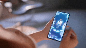 Celebrity gif. Noa Kirel swipes through a futuristic phone, with multiple videos of her dancing in different outfits.