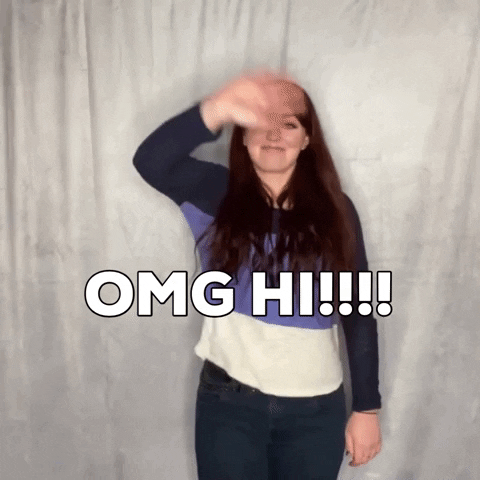 Celebrity gif. Kathryn Dean stands in front of a white curtain to wave at us enthusiastically. Text, "OMG hi!!!!"