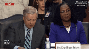 Meme gif. Two gifs. First: Senator Lindsey Jackson at his seat during the confirmation hearing for Ketanji Brown Jackson shuffles two pieces of paper together before putting them down, one labeled "dog whistle" and the other labeled "grand standing." Second: Ketanji Brown Jackson, during her confirmation hearing, smiles slightly and takes a deep breath, a look of composed patience on her face.