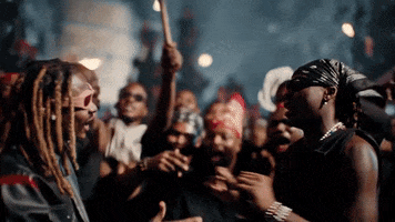 Video gif. An crowd surrounds two men with torches. The two men hug and the crowd cheers excitedly.