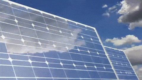 Some clouds, which run across the sky, appear reflected on solar panels. The clouds run fast. 