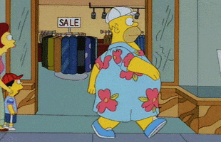 The Simpsons gif. Homer struts in a blue flowered dress down a sidewalk as a man turns to gaze at him. 