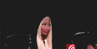 Celebrity gif. We zoom in on Nicki Minaj as she purses her lips and flutters her lashes with a side eye.