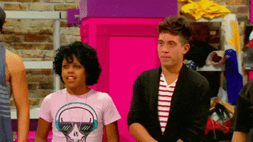 Reality TV gif. The camera pans over the contestants on RuPaul's Drag Race and we see their shocked expressions one by one.