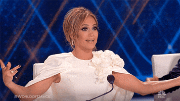 Reality TV gif. Jennifer Lopez is a judge on World of Dance. She outstretches her arms confidently before bringing them back to her chest and covering her mouth with her hands, giggling.