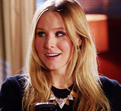 TV gif. Kristen Bell as Veronica on Veronica Mars open-mouth smiles as she turns her eyes towards us and winks.