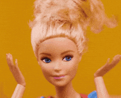 Video gif. A closeup on a Barbie doll with its hair up as its hands move to its mouth in "surprise".