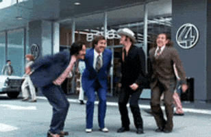 Movie gif. Four men in "Anchorman" stand in front of channel 4 building and jump for joy simultaneously.