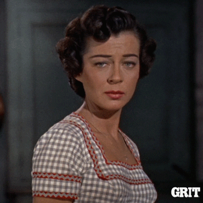 Movie gif. Gail Russell as Annie Greer has a worried expression on her face and looks away as if hiding her annoyance. 