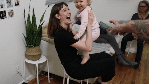 a woman is holding a baby in her arms in a living room .