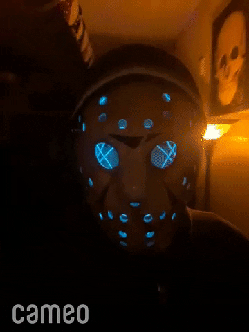 Video gif. Scary Cameo video with a person in a glowing, flashing hockey mask, walking through a house.