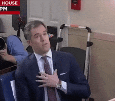 Video gif. Media reporter sits and looks up at someone as if he’s been offended with his hand on his chest in shock. He then motion his hands around, and squints his eyes in confusion.