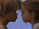 Movie gif. Anna Chlumsky as Vada and Macaulay Caulkin as Thomas in My Girl are in front of a lake and share a small smooch before separating with surprise on their faces.